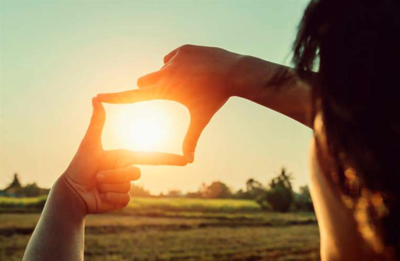 Person framing the sun with her hands